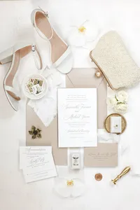 Wedding invitation suite styled with bridal heels, pearls and a beaded clutch