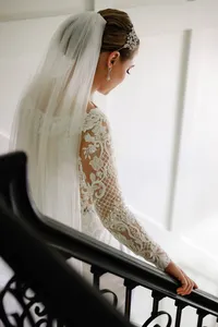 Bride in a lace gown with a cathedral veil walking down a staircase