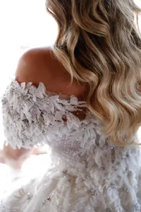 Bride in an off-the-shoulder textured gown with soft waves in her hair