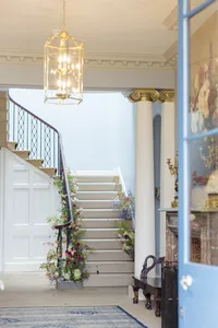 Sweeping staircase dressed in flowers beneath a lantern in an elegant wedding venue