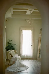 Wedding gown draped over a chair beneath an arched doorway, shot on film