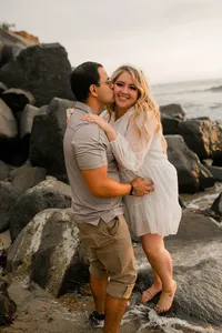 Couple embracing on coastal rocks at sunset during their Sunset Cliff portrait session