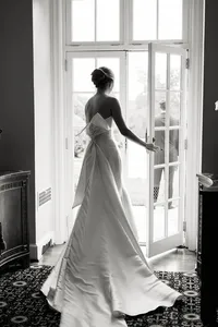 A refined composition of a bride in a statement gown standing in a sunlit doorway, captured with an editorial and intentional eye.