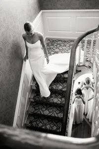 A refined composition of a bride descending a staircase to meet her bridesmaids, capturing a genuine connection and real moment.