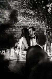 Authentic documentary moment of a bride and groom kissing at a candlelit reception table at the Wythe Hotel in Brooklyn.