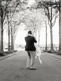 A high-contrast black and white shot of a groom lifting the bride, capturing a real moment of joy with a natural motion blur.