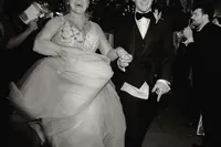 Bride and groom hold hands and running during their new years eve wedding exit as guests cheer around them.