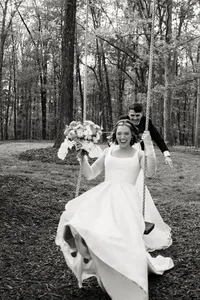 A whimsical black and white moment of a bride on a swing, preserving the atmosphere and emotion of an intentional outdoor celebration.
