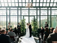 A wide shot of a couple’s first kiss in a glass-walled chapel, capturing the preserving atmosphere and emotion of the ceremony.