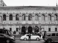 A wide black and white street scene in front of the Boston Public Library, capturing a genuine connection amidst the urban energy.