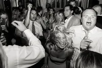 A high-energy, documentary style wedding photography capture of guests dancing and singing at a luxury coastal reception.