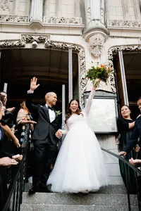 A documentary style wedding photography capture of a couple cheering as they exit St. Vincent Ferrer in New York City.