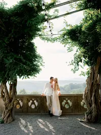 A couple leaning against an ornate stone balcony, illustrating the refined composition and heirloom quality of an estate wedding weekend.