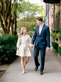 A documentary style wedding photography shot of a couple walking past historic Charleston architecture, showcasing a refined composition.