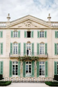A wide, refined composition of a couple on a chateau balcony, highlighting the intentional imagery of a multi-day wedding celebration at Chateau de Tourreau.