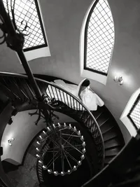 Dramatic high-angle editorial photograph of a bride descending the grand spiral staircase at Dover Hall Estate.