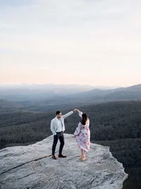 A wide-angle, intentional imagery capture of a couple dancing on a cliffside, highlighting the vast landscape of an East Coast mountain celebration on Blue Ridge Parkway.