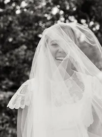 A close-up, joyful real moment of a bride laughing under her veil, preserving the atmosphere and emotion of a Charleston wedding morning.