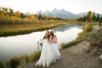 Bride and bride share a kiss in front of the grand tetons at swabacher's landing