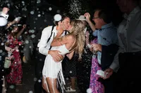 couple shares a kiss as they exit their wedding with confetti flying around them