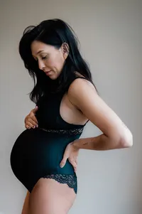 Een intieme zwangerschapsfotoshoot binnenshuis, waarbij een moeder trots haar groeiende buik toont, vastgelegd door Monica Stout Fotografie.