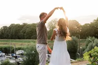Een stel danst bij zonsondergang langs een rivier tijdens een loveshoot, vastgelegd door Monica Stout Fotografie in een romantische setting.
