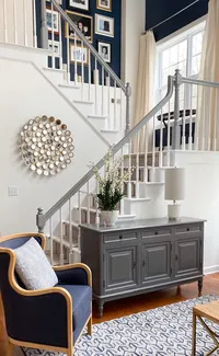 navy blue paint on walls up the stairs. Gallery wall on staircase. Living room with navy blue accent wall. Gracious Home Interiors - Luxury residential interior design firm in Waxhaw North Carolina.