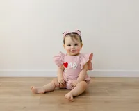 Pink romper, sweet smile, and a heart full of birthday joy. Captured by Yucaipa cake smash photographer Kaitlyn Dawn Photography.