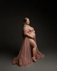 Expecting mother sitting in a flowing maternity gown during a studio maternity portrait by Kaitlyn Dawn Photography in Yucaipa.