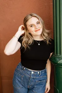 High school senior girl standing against a textured wall in natural light, casual senior portrait by Kaitlyn Dawn Photography.