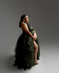Studio maternity portrait of expecting mother wearing a dark emerald green maternity gown posing in profile with hands on baby bump photographed by Yucaipa best maternity photographer Kaitlyn Dawn Photography.