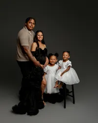 Family maternity portrait with parents and two young daughters wearing white dresses during a studio pregnancy photography session by Kaitlyn Dawn Photography.