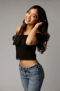 High school senior girl with long dark hair wearing a black top and jeans posing in a studio, studio senior portrait by Kaitlyn Dawn Photography.
