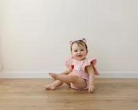 She wore her heart on her romper and her joy in every smile. Captured by Yucaipa cake smash photographer Kaitlyn Dawn Photography.