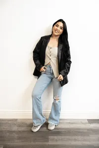 Branding portrait of tattooed woman with long dark hair smiling while seated. Photograph by Yucaipa branding photographer Kaitlyn Dawn Photography.