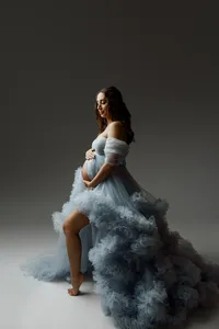 Expecting mom in a dramatic blue maternity dress standing gracefully with her hand on her belly, photographed in Yucaipa by Kaitlyn Dawn Photography.