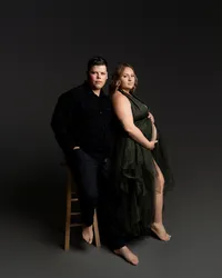 Expecting couple posing together during a studio maternity photoshoot by Kaitlyn Dawn Photography.