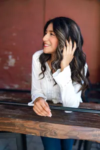 High school senior girl looking to the side while leaning on a wooden railing, natural light senior portrait by Kaitlyn Dawn Photography.