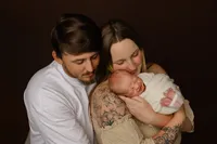 Parents cuddling their newborn baby during a warm studio portrait session. Photographed by Inland Empire newborn photographer Kaitlyn Dawn Photography.
