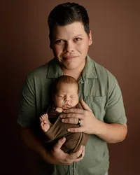 Father holding his sleeping newborn baby during a warm studio newborn family portrait session in Inland Empire by Kaitlyn Dawn Photography.