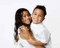 Two smiling siblings hugging during a studio children’s portrait session with Kaitlyn Dawn Photography at Yucaipa.