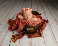 Newborn baby posed in a rustic wood bowl with warm rust and cream textures. Photographed by Inland Empire newborn photographer Kaitlyn Dawn Photography.