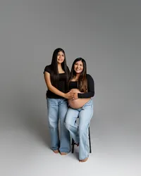 Pregnant woman posing with her daughter while seated, both smiling and holding her baby bump during an Inland Empire maternity session by Kaitlyn Dawn Photography.