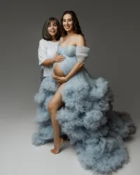 Pregnant woman smiling with her mother touching her belly, wearing a blue maternity gown during a heartfelt pregnancy session by Kaitlyn Dawn Photography in Yucaipa.