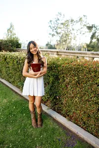 High school senior girl in a white dress and cowboy boots standing in a garden path, outdoor senior portrait by Kaitlyn Dawn Photography.