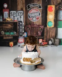 Baby boy digging into his birthday cake headfirst during a rustic, automotive-themed first birthday shoot.
Photograph by Yucaipa cake smash photographer Kaitlyn Dawn Photography.