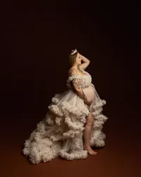 Pregnant woman in a flowing cream tulle maternity gown posing during a studio maternity photoshoot by Kaitlyn Dawn Photography.