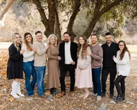 Large extended family standing together outdoors under tall trees with warm fall tones, natural light portrait by Kaitlyn Dawn Photography, professional extended family photographer specializing in timeless group portraits.