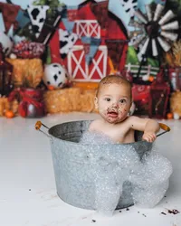 Baby with chocolate on their face enjoying a bubble bath in a metal tub after cake smash. Photograph by Yucaipa cake smash photographer Kaitlyn Dawn Photography.