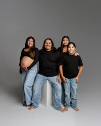 Studio maternity family portrait with expecting mother, father, and two children in coordinated outfits photographed by Kaitlyn Dawn Photography.